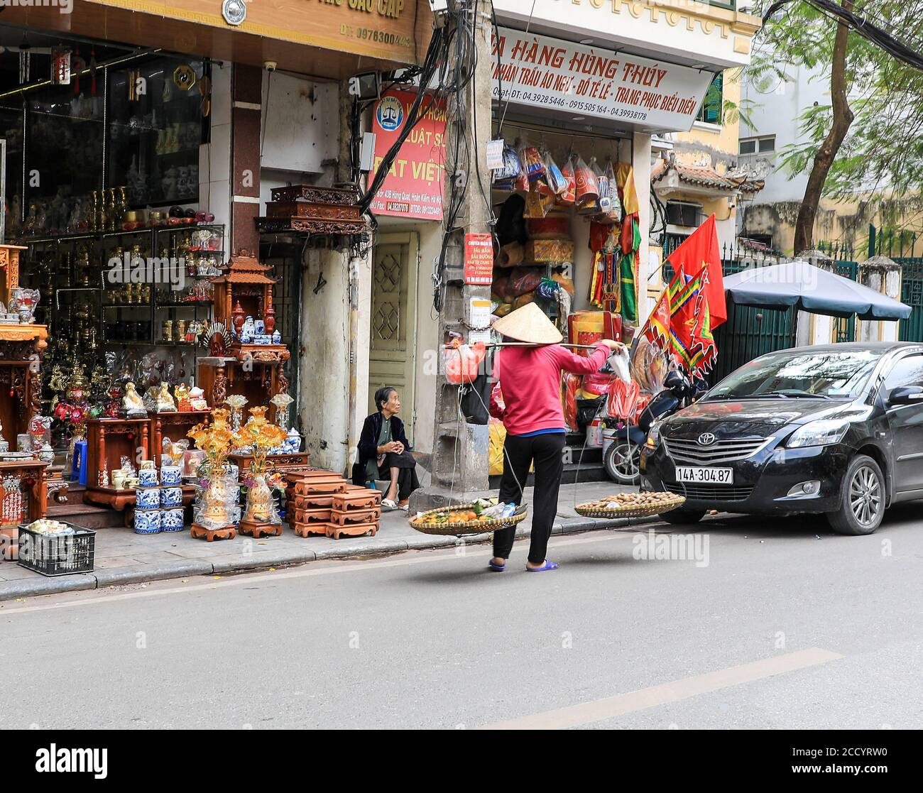 Ein Händler oder Straßenverkäufer trägt einen vietnamesischen konischen Hut (nón lá) Verkauf von Obst und Nüssen, Hanoi, Vietnam, Asien Stockfoto