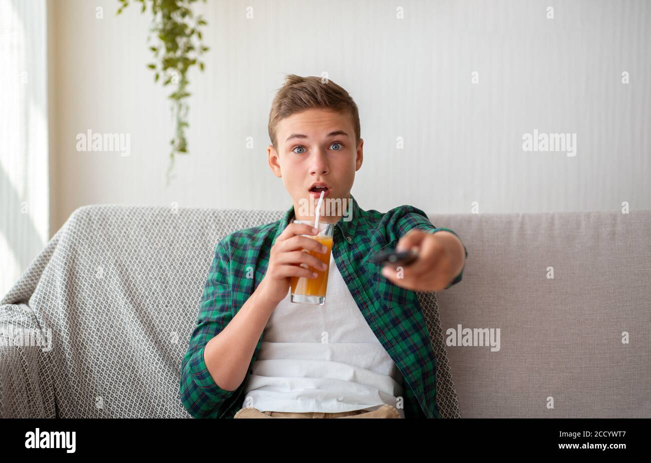 Schockiert teen junge trinken Saft und Film Stockfoto