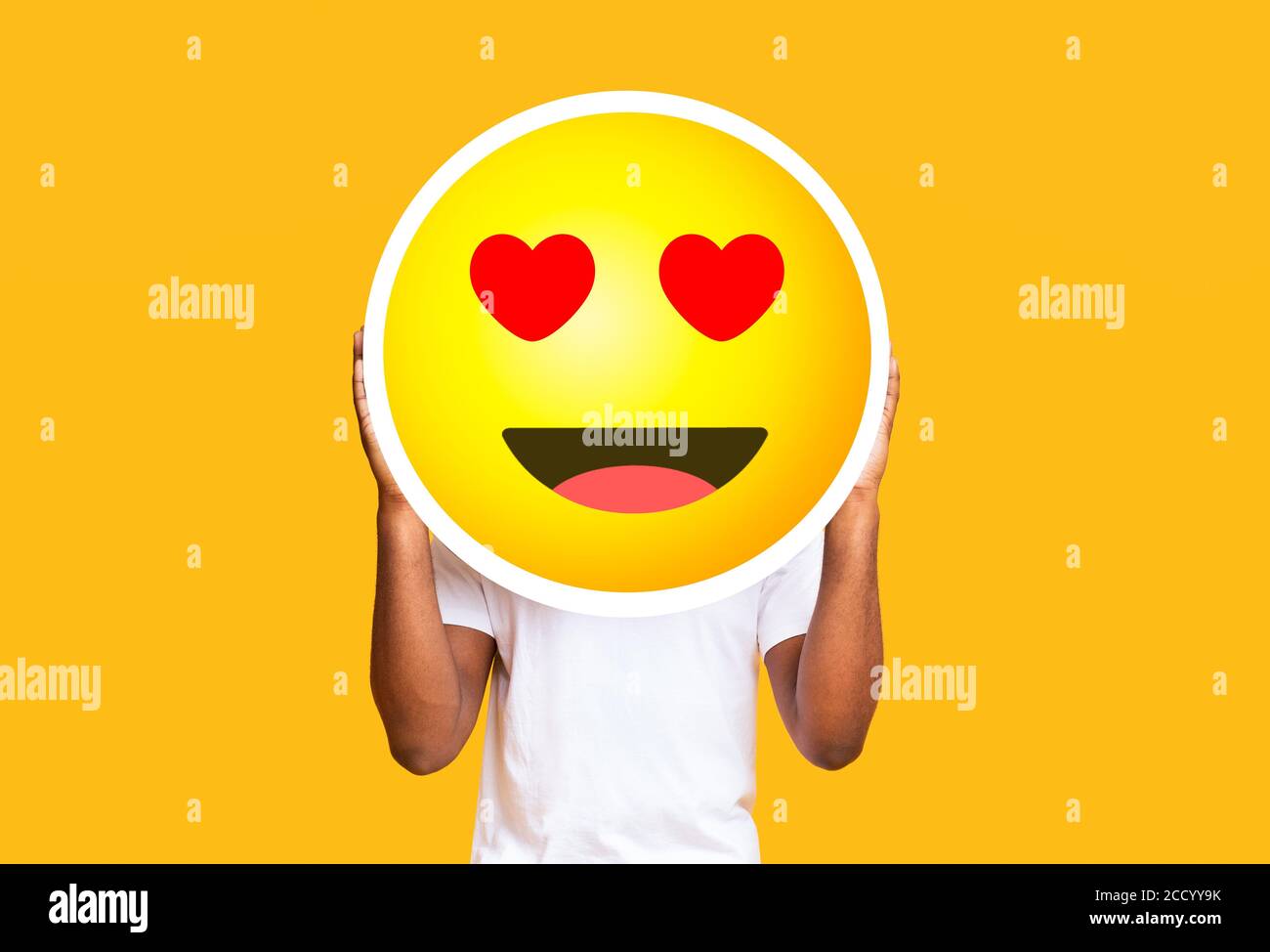 Unkenntlich schwarzer Mann versteckt Gesicht gegen in der Liebe Emoticon emoji Stockfoto