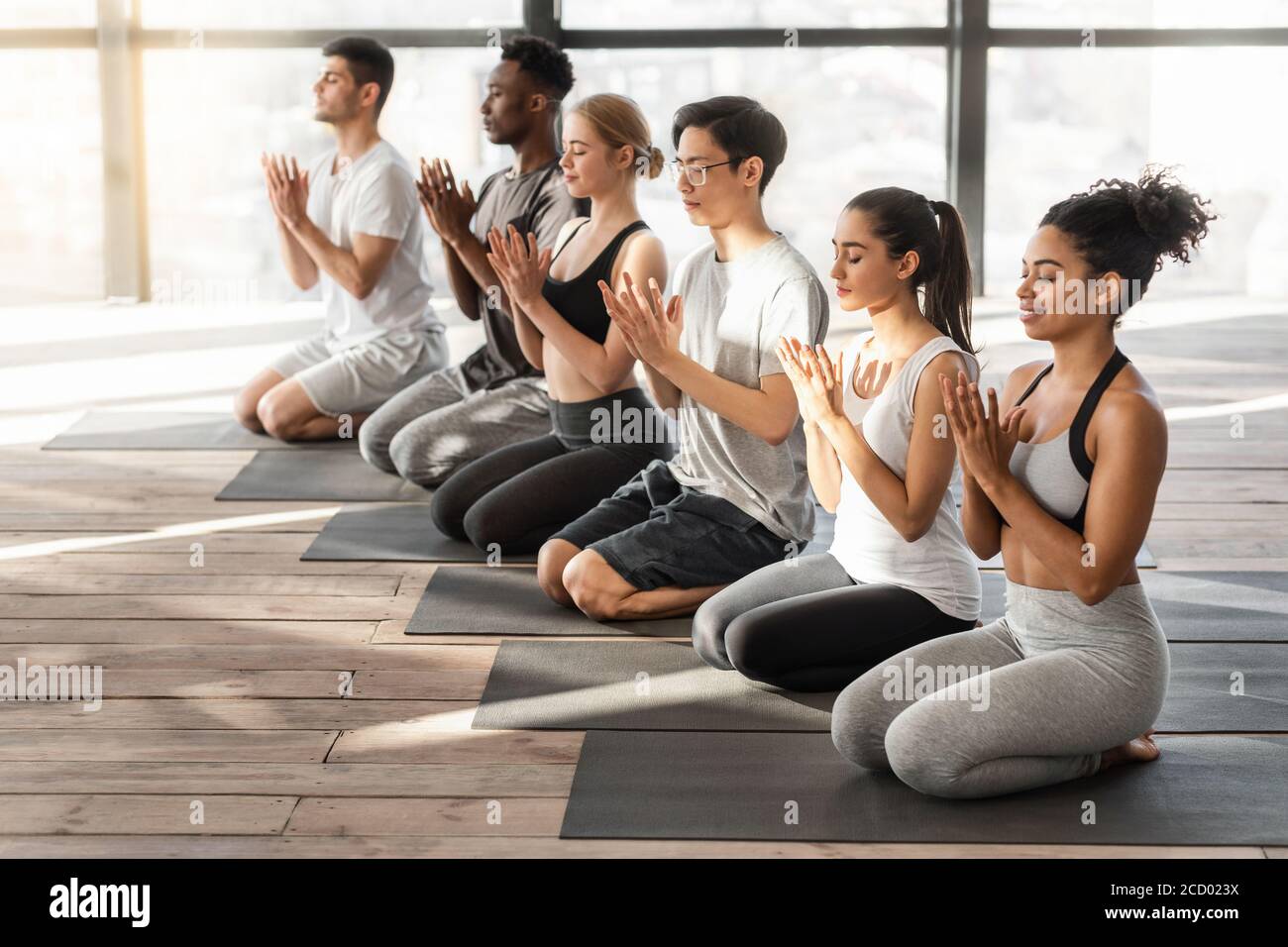 Yoga-Unterricht. Gruppe von sportlichen Menschen tun Lotusrobbe Geste im Studio Stockfoto