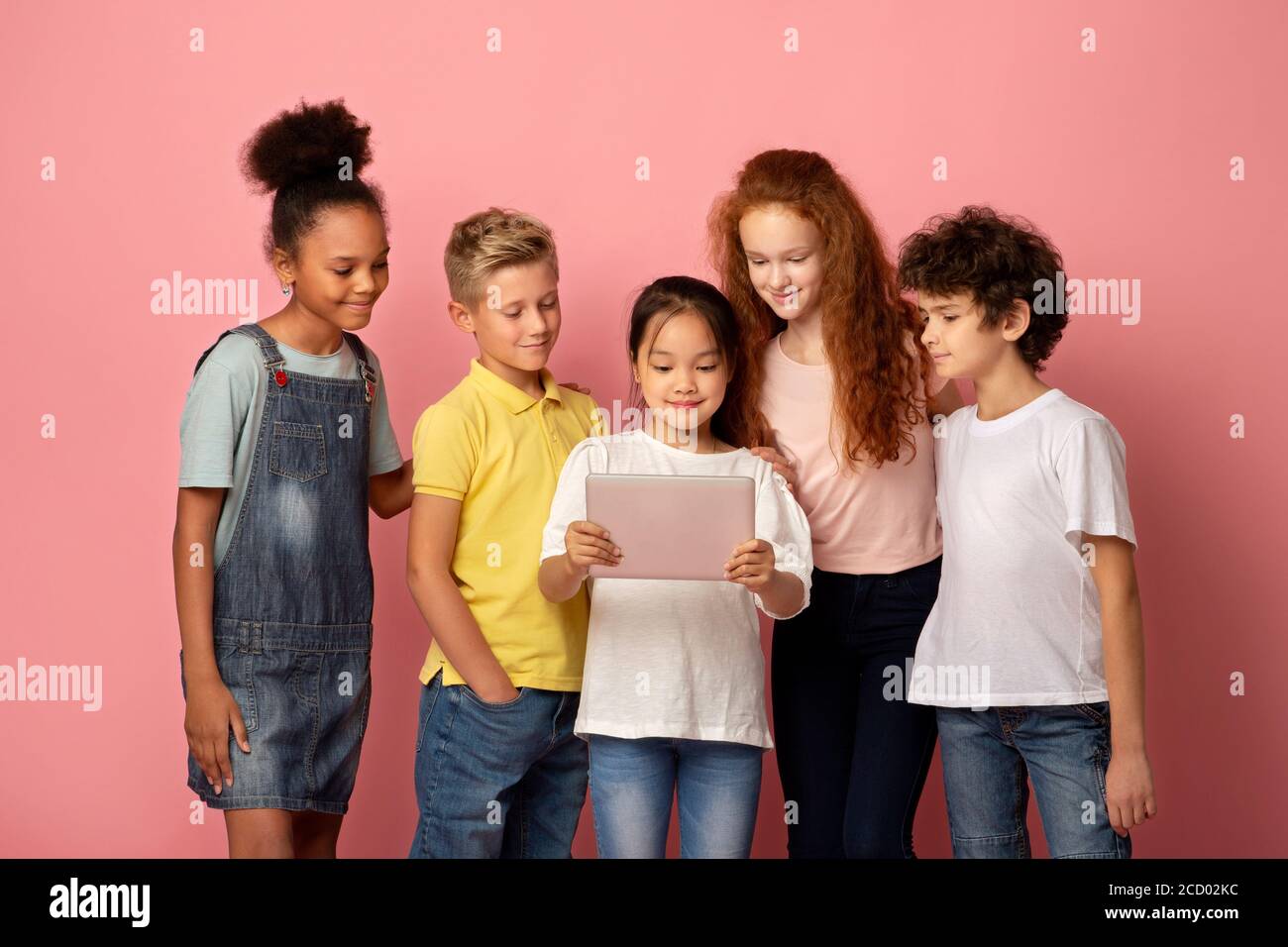 Multinationale junge Studenten mit Tablet-Computer zusammen zu studieren über Rosa Hintergrund Stockfoto