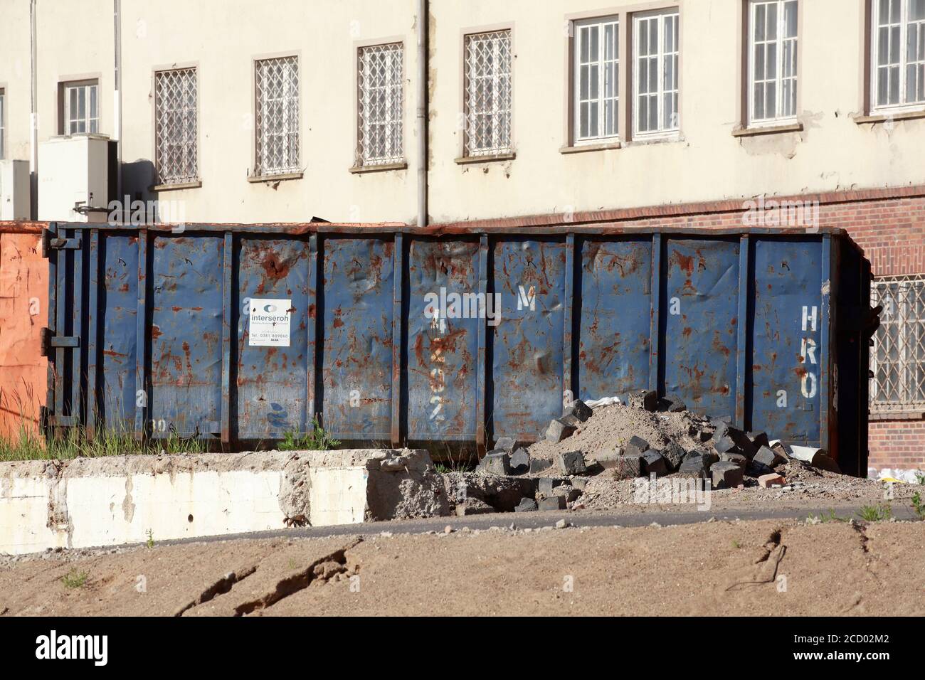 Container für Bauabfälle auf einer Baustelle vor einem baufälligen Haus, Rostock, Mecklenburg-Vorpommern, Deutschland, Europa Stockfoto