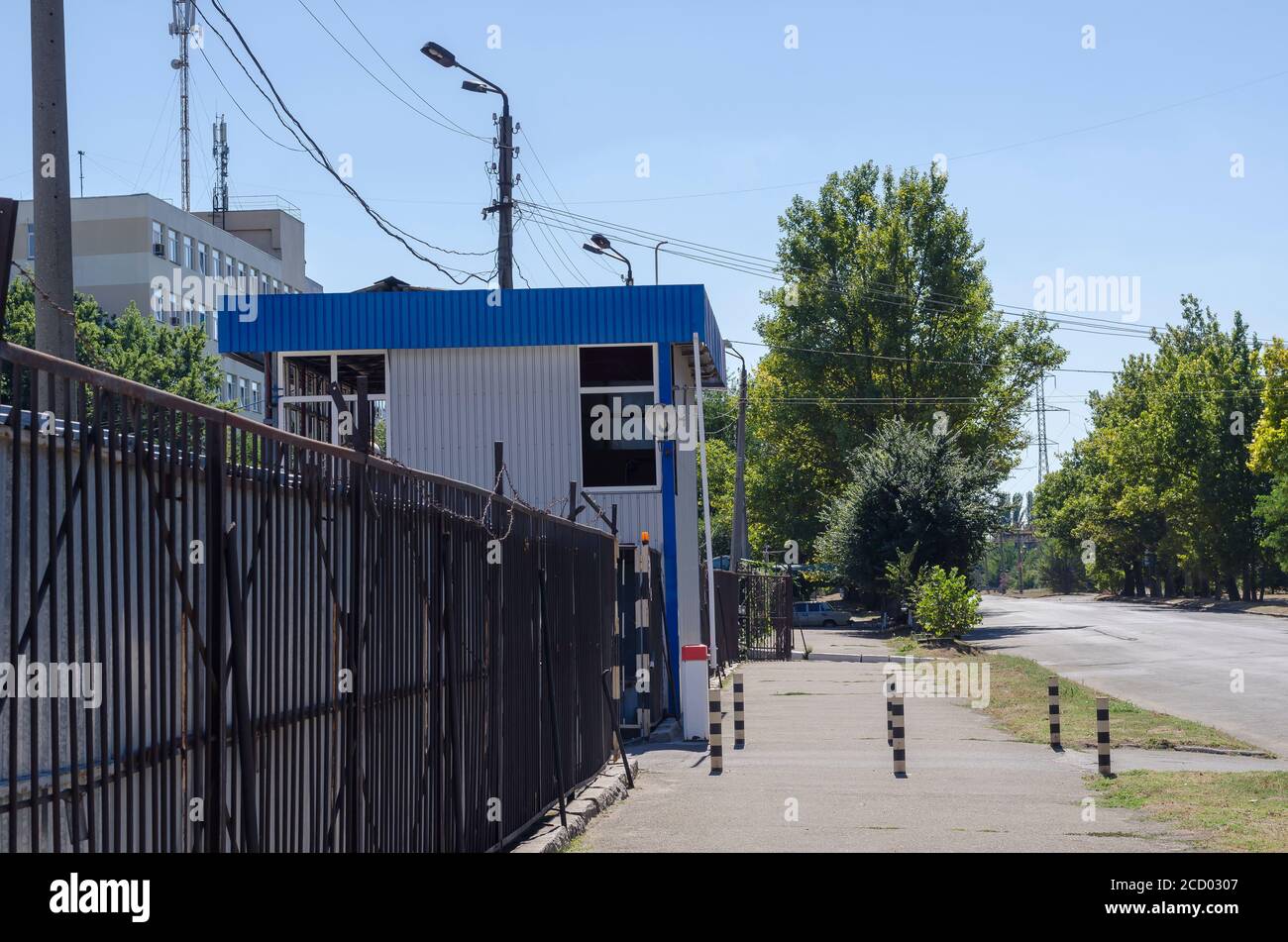 Eingang zum bewachten Parkplatz. Metallzaun mit Stacheldraht. Eingang mit Schranke. Ohne jemanden. Selektiver Fokus. Stockfoto