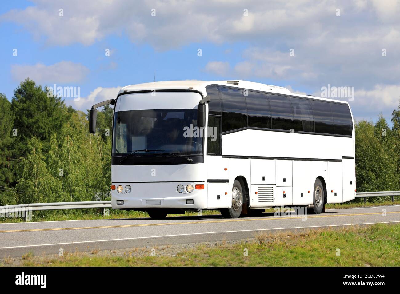 Weißer Reisebus fährt entlang der Autobahn an einem schönen Tag des Sommers, blauer Himmel und Wolken Hintergrund. Stockfoto