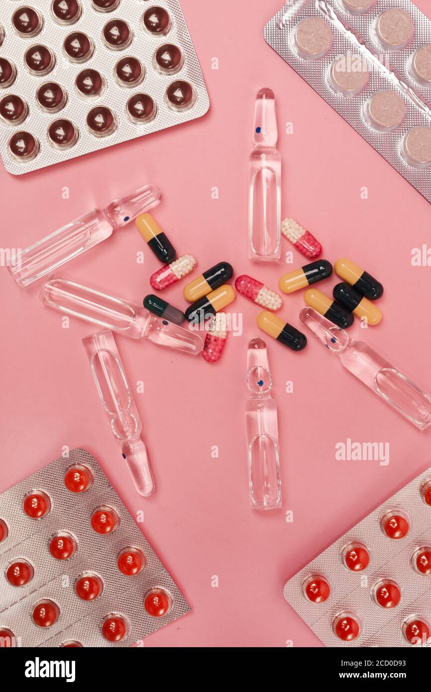 Vertikale Ansicht von oben nach unten auf flacher Lage von Medikamentenkapseln, Pillen und Thermometer auf rosa Hintergrund, covid und Grippe-Konzept, Kopierraum Stockfoto