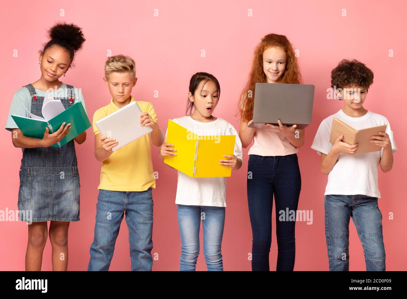 Zurück zur Schule. Multiethnische Kinder mit Gadgets, Büchern und Notizbüchern auf rosa Hintergrund Stockfoto