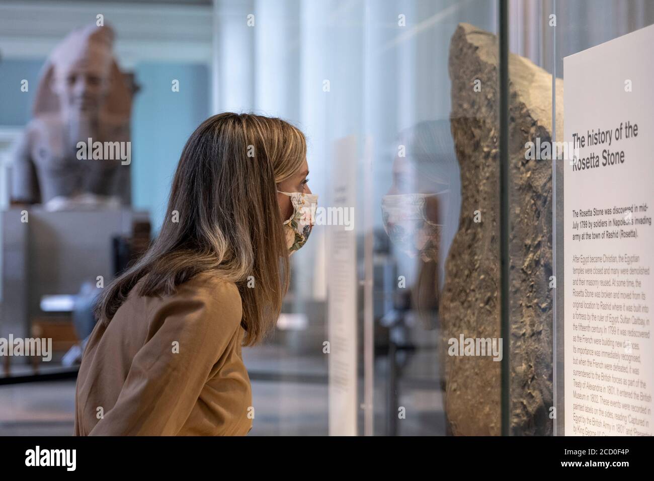 London, England. August 2020. Eine Frau, die eine Gesichtsbedeckung trägt und den Rosetta Stone im British Museum betrachtet. Das British Museum wird seine Türen für die Öffentlichkeit im Einklang mit den Richtlinien der Regierung und mit neuen Sicherheitsmaßnahmen wieder öffnen. Nach fünf Monaten Schließung aufgrund der Coronavirus-Pandemie wird das British Museum am 27. August 2020 seine Pforten wieder für die Öffentlichkeit öffnen. Eine neue Einbahnstraße rund um die Galerien im Erdgeschoss ermöglicht den Besuchern den Zugang zu über 9000 Objekten. Weitere Galerien werden später im September wieder eröffnet. (Foto von Sam Mellish / Alamy Live Ne Stockfoto