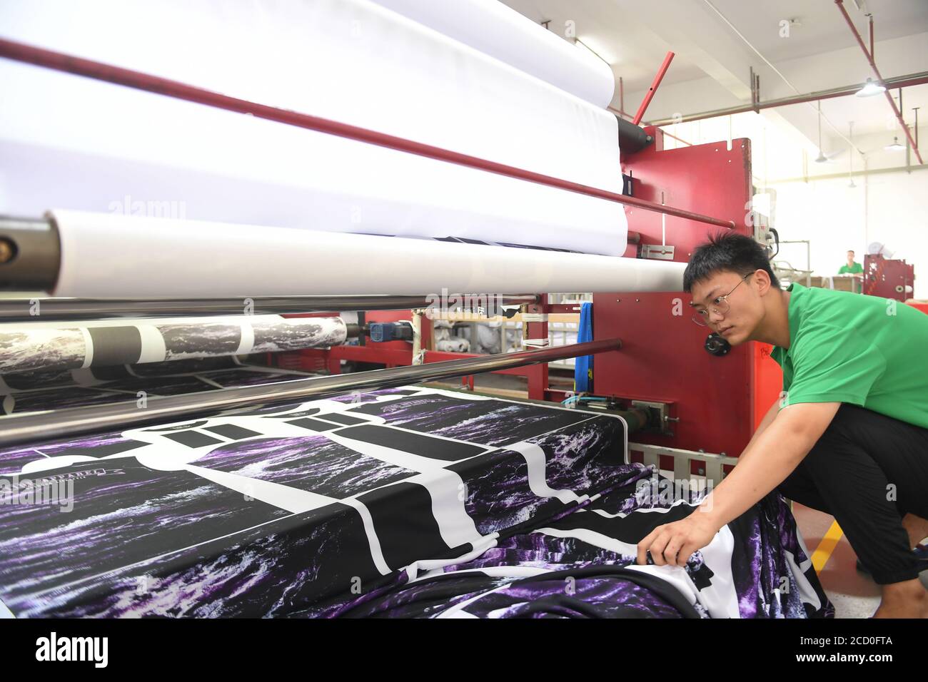 Shishi, Chinas Provinz Fujian. August 2020. Ein Arbeiter betreibt eine Maschine, um Muster auf Kleidung in einem Bekleidungsunternehmen in Shishi, südöstlich der Provinz Fujian in China, aufzudrucken, 25. August 2020. Die lokalen Behörden von Shishi, wo viele Textilunternehmen ansässig sind, haben einige günstige Maßnahmen durchgeführt, um die Kosten zu senken und den Unternehmen zu helfen, die Produktions- und Vermarktungsstrategien anzupassen. Die Produktionskapazität der Textilunternehmen hat sich stark verbessert. Quelle: Song Weiwei/Xinhua/Alamy Live News Stockfoto