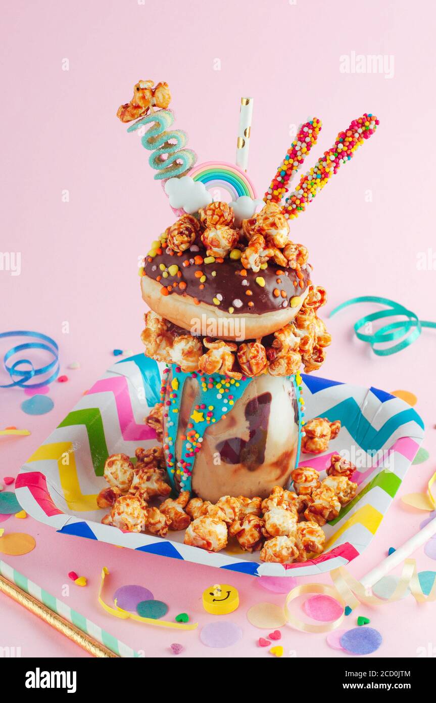 Kids Party Konzept: Schokofreak Shake Topping mit Donut und Karamell Popcorn auf dem Kids Party Tisch; selektiver Fokus. Stockfoto