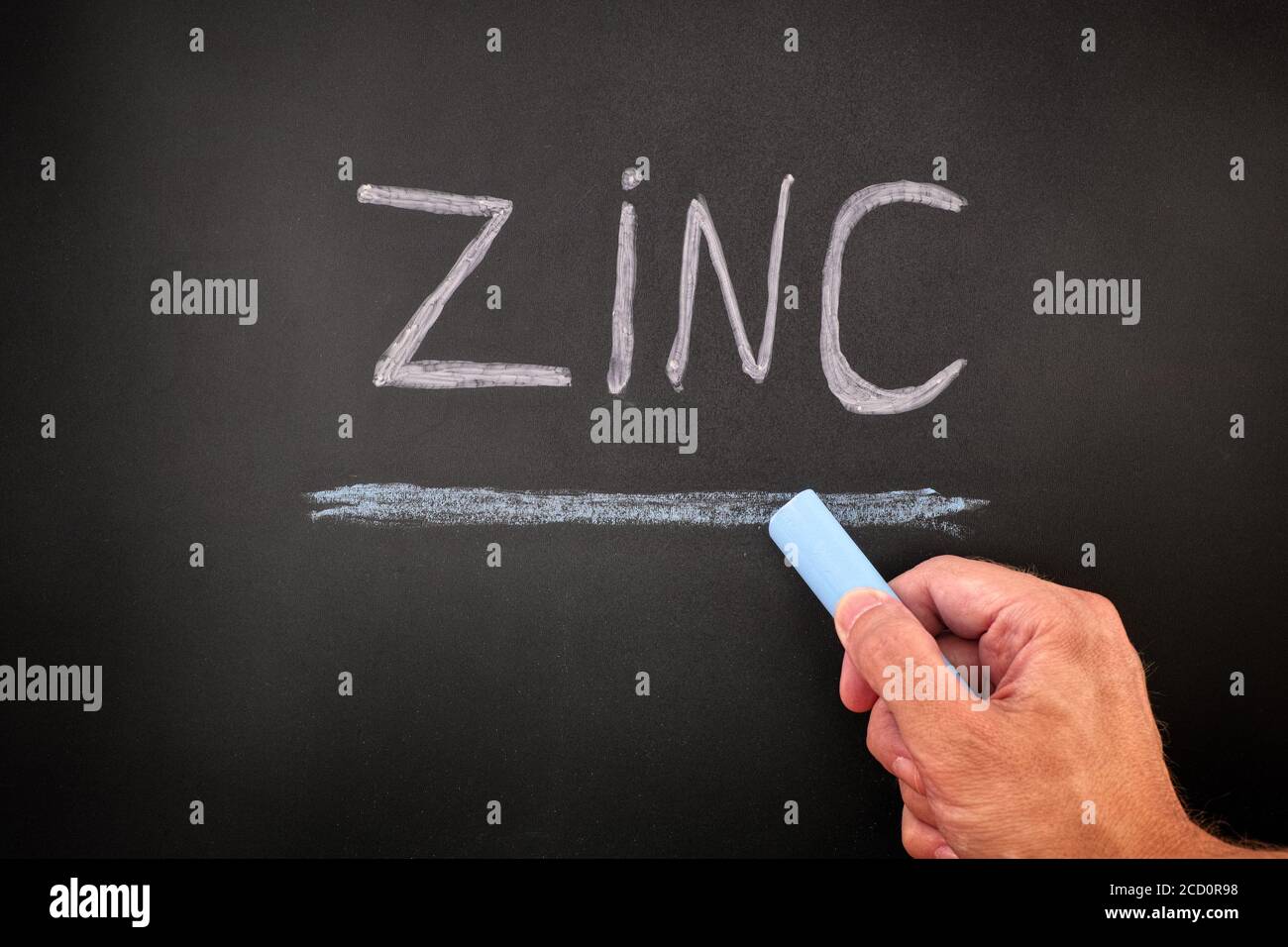 Mann, der das Wort Zink auf eine Tafel schreibt. Nahaufnahme. Stockfoto