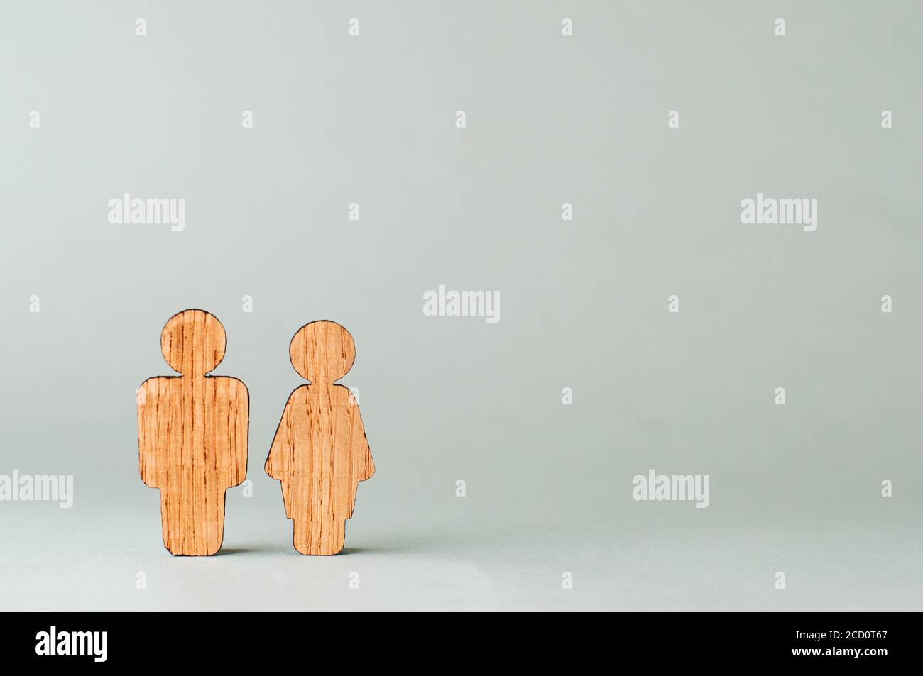 Holzfiguren von Mann und Frau auf grauem Hintergrund mit Leerzeichen für Text. Stockfoto