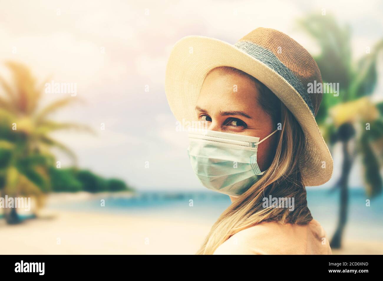 Junge Frau mit Schutzmaske am tropischen Strand. Covid-19 oder Coronavirus Pandemie. Sommerreise mit neuen normalen Stockfoto