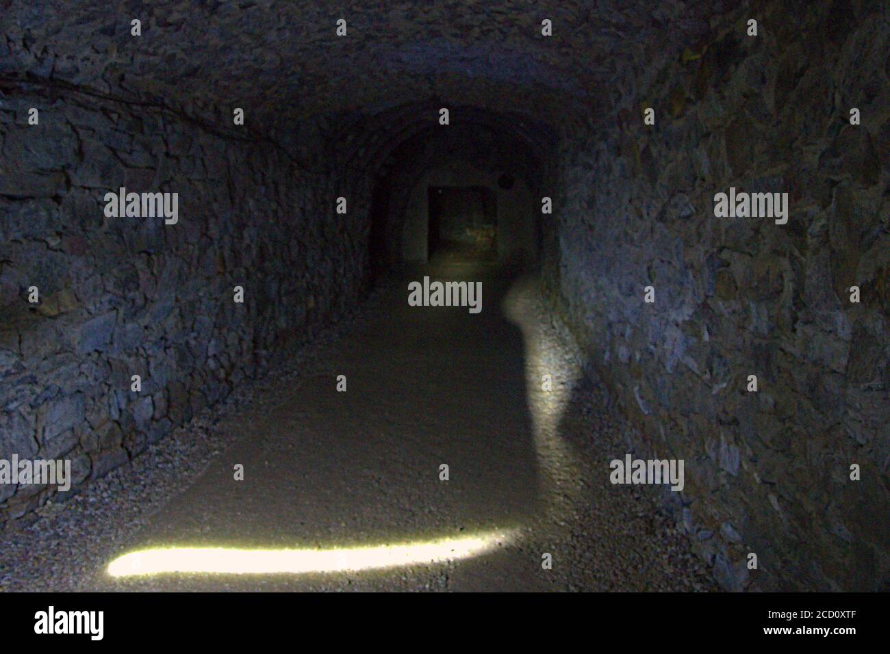 Ein leerer Tunnelweg, der von einer Fackel in einem beleuchtet wird Verlassene Uranmine Stockfoto