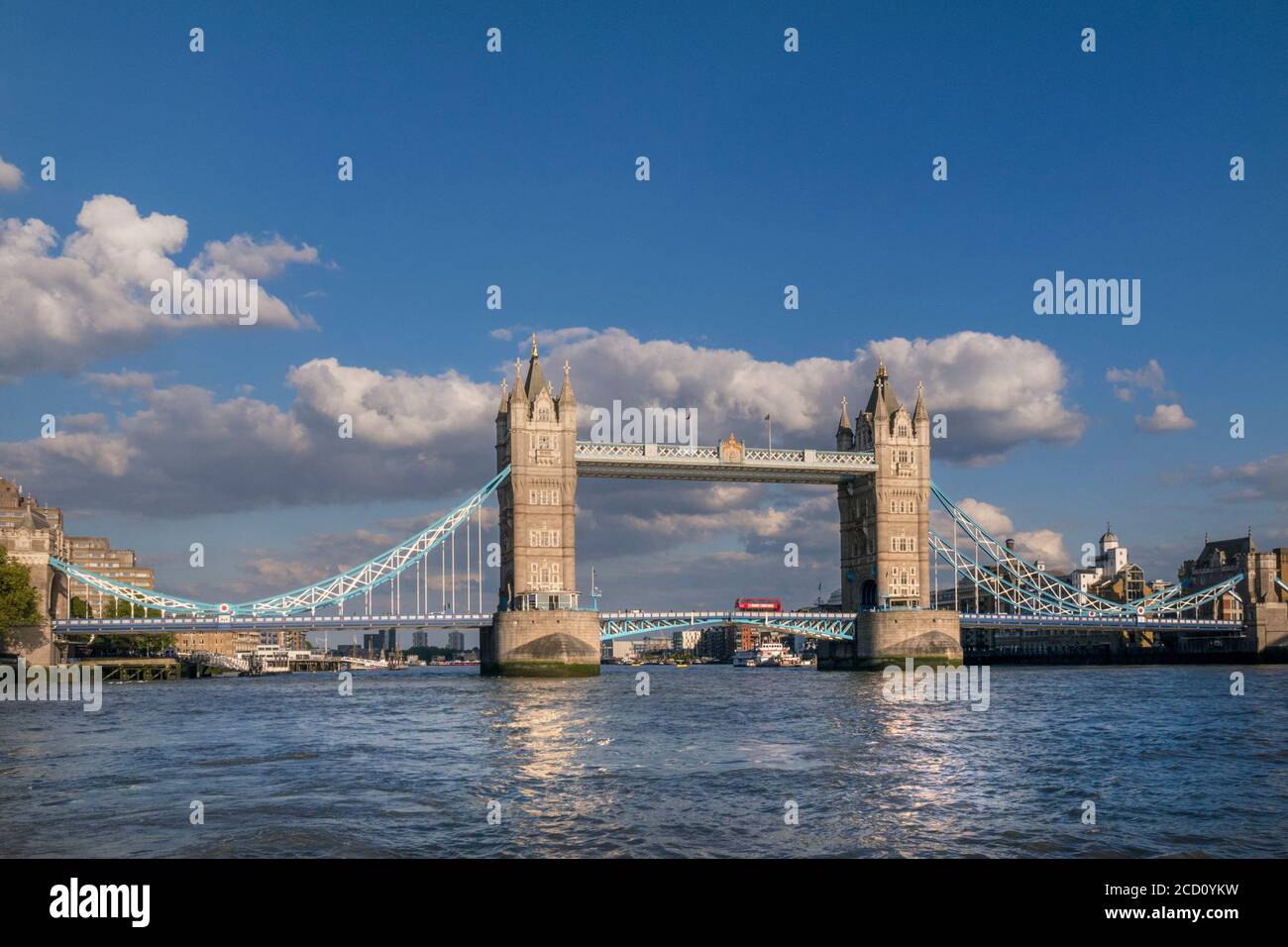 Tower Bridge weiten Blick Landschaft mit roten Londoner bus überqueren die Brücke und den Fluss Themse, gesehen von einem RB1 Pendler River Boat am späten Nachmittag Sonne. Southwark London UK Panorama Vista Stadtblick Attraktion mit klaren blauen Himmel. Die Tower Bridge ist eine kombinierte Klapp- und Hängebrücke in London, zwischen 1886 und 1894 gebaut. Die Brücke überquert den Fluss Themse in der Nähe des Tower von London und hat eine Ikone und bleibendes Symbol der London England Großbritannien UK werden Stockfoto