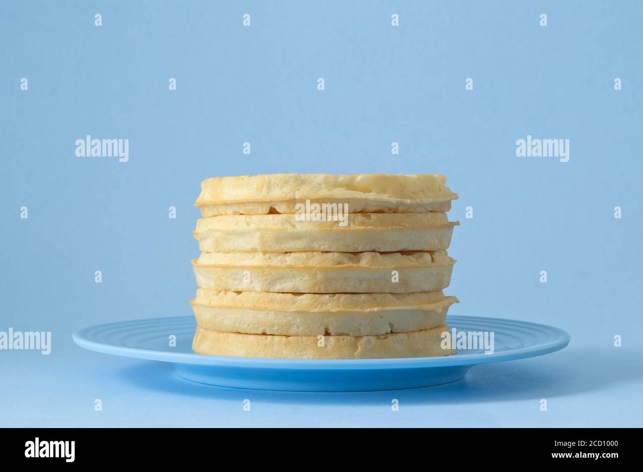 Runde Waffeln zum Frühstück auf blauem Teller gestapelt Stockfoto