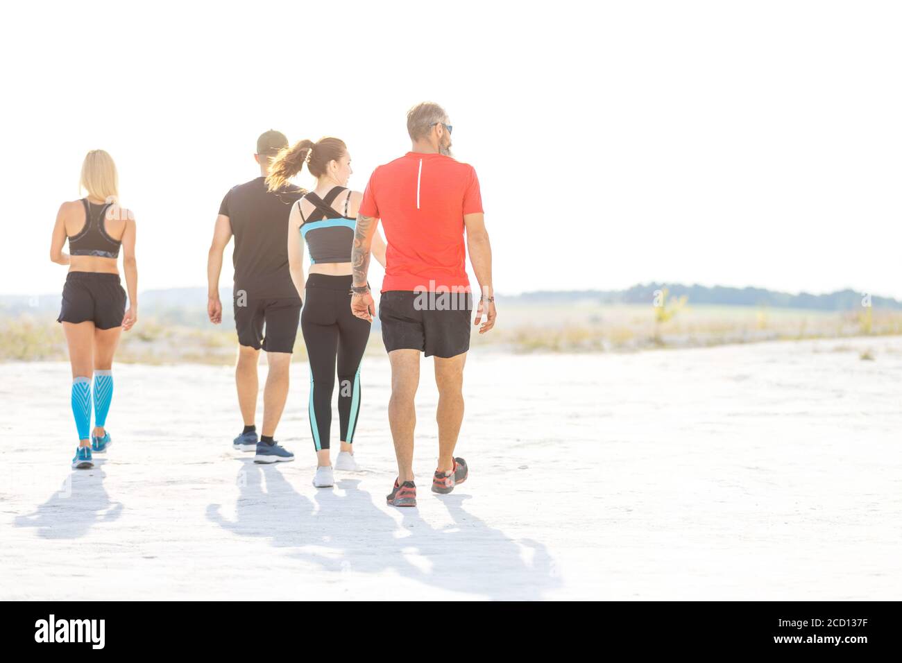 Gruppe von vier Läufern wandern auf sandigen Wüstenland. Konzept Läufer Bild mit Kopierraum Stockfoto