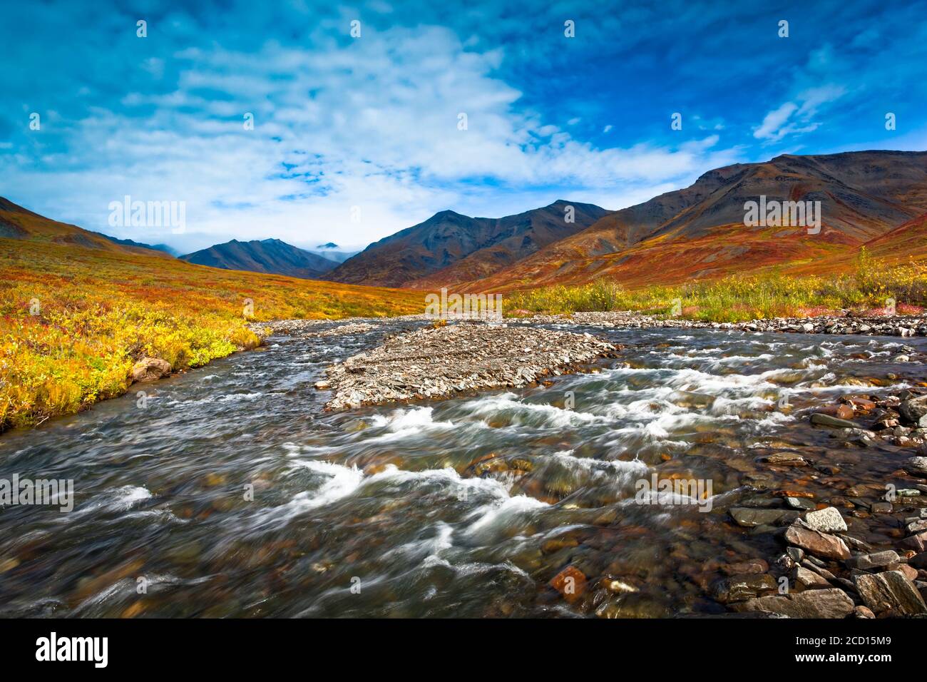 Kuyuktuvuk Creek und Brooks Mountains in Herbstfarben unter blauem Himmel. Tore des Arctic National Park and Preserve, Arctic Alaska im Herbst Stockfoto