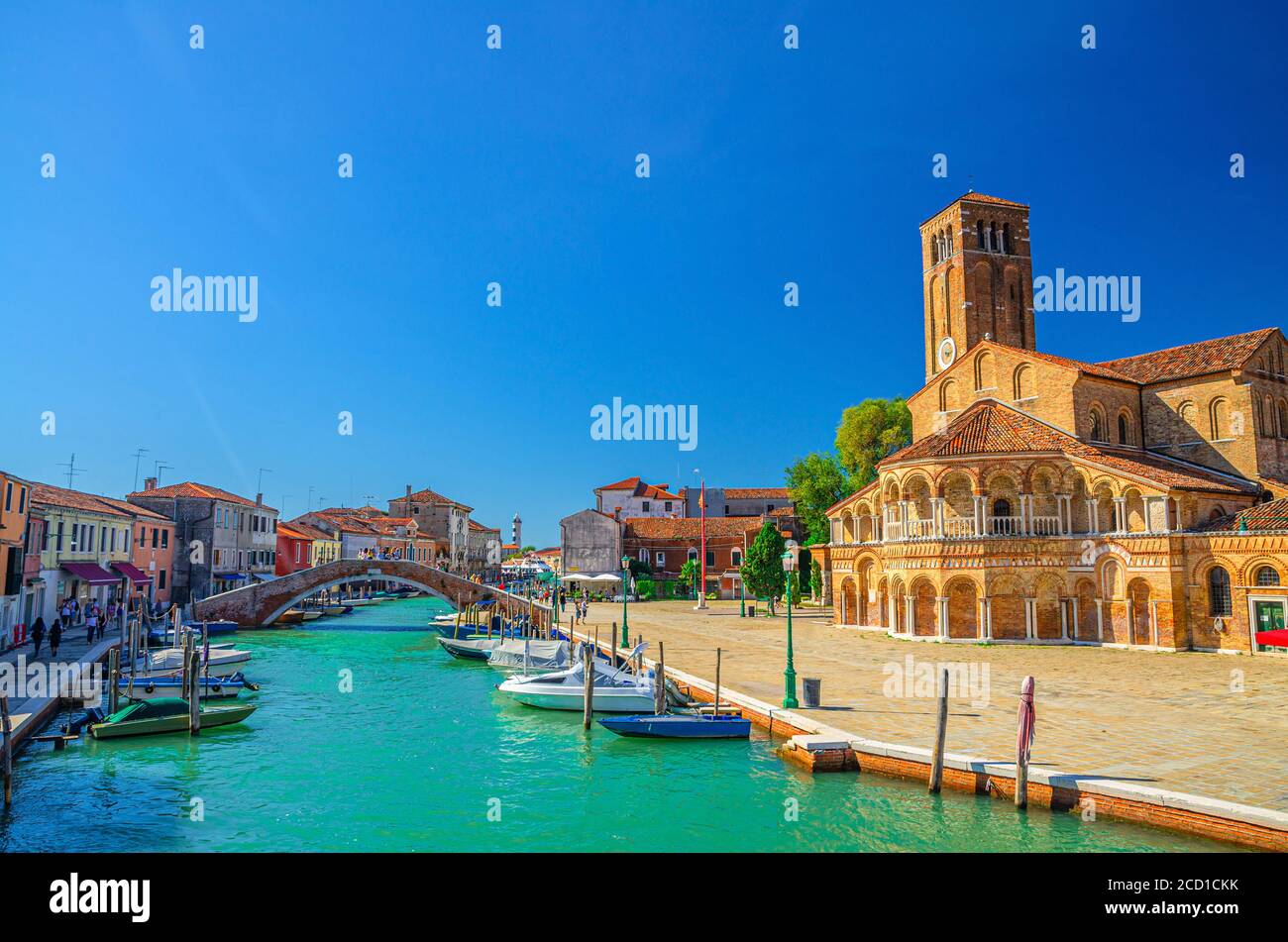 Stadtbild der Murano-Inseln mit Kirche Santa Maria e San Donato und Glockenturm Backsteingebäude, Brücke über den Wasserkanal mit Motorbooten, Region Venetien, Norditalien. Murano-Postkarte. Stockfoto