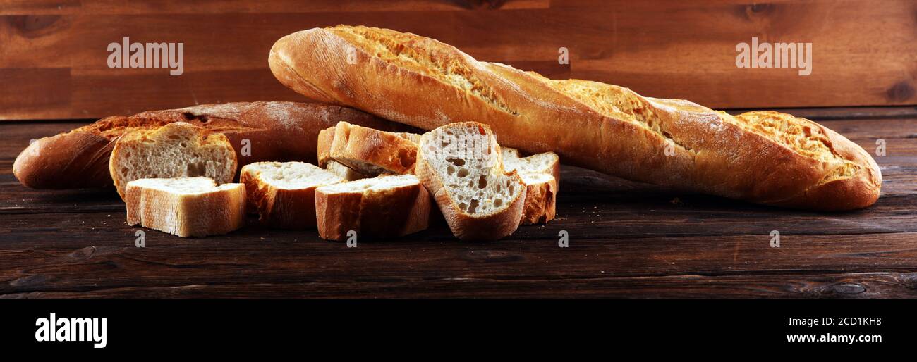 Baguette gebackenes Brot und geschnittenes Baguette auf Holzhintergrund Stockfoto