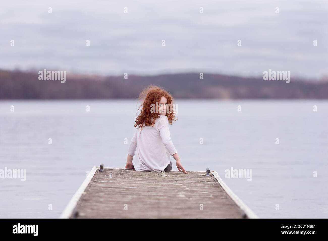 Mädchen sitzt auf einem Dock Stockfoto