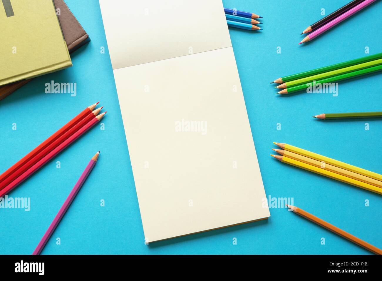 Schulkonzept. Bunte Buntstifte, Bücher und offenes Skizzenbuch auf blauem Papierhintergrund. Flach liegend, freier Platz für Text oder Bild Stockfoto