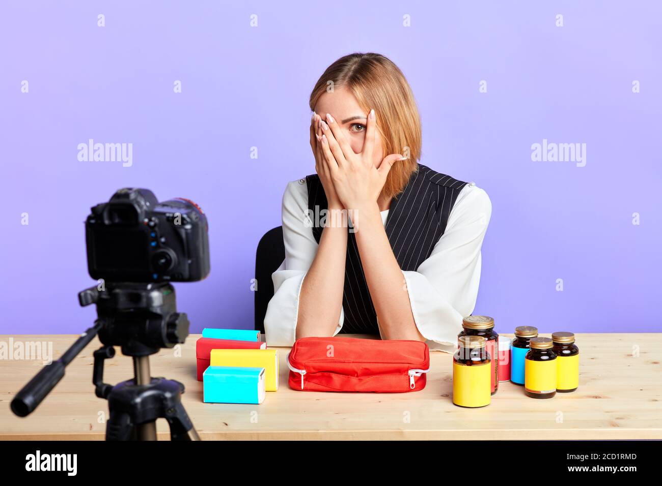 Isolierte Sicht auf müde weibliche Modell schließt ihr Gesicht mit den Händen, ein Auge auf die Kamera, fühlt sich erschöpft und aus der Energie nach langen Drehtag, nehmen Stockfoto