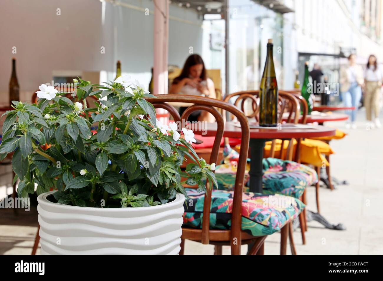 Straßencafé in einer Stadt, Tische mit Flaschen in einem Restaurant im Freien, elegante Umgebung für Feier und Datum. Topf mit Blumen und Vintage-Stühle Stockfoto