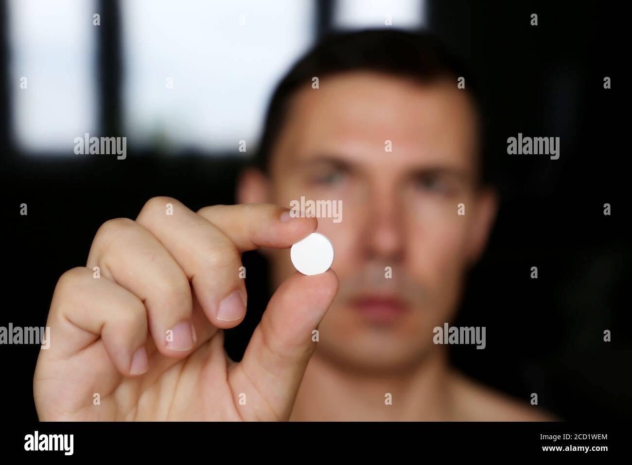 Mann mit weißer Pille, männliche Hand mit Medikamenten aus nächster Nähe. Konzept von Antibiotika oder Vitamin Stockfoto