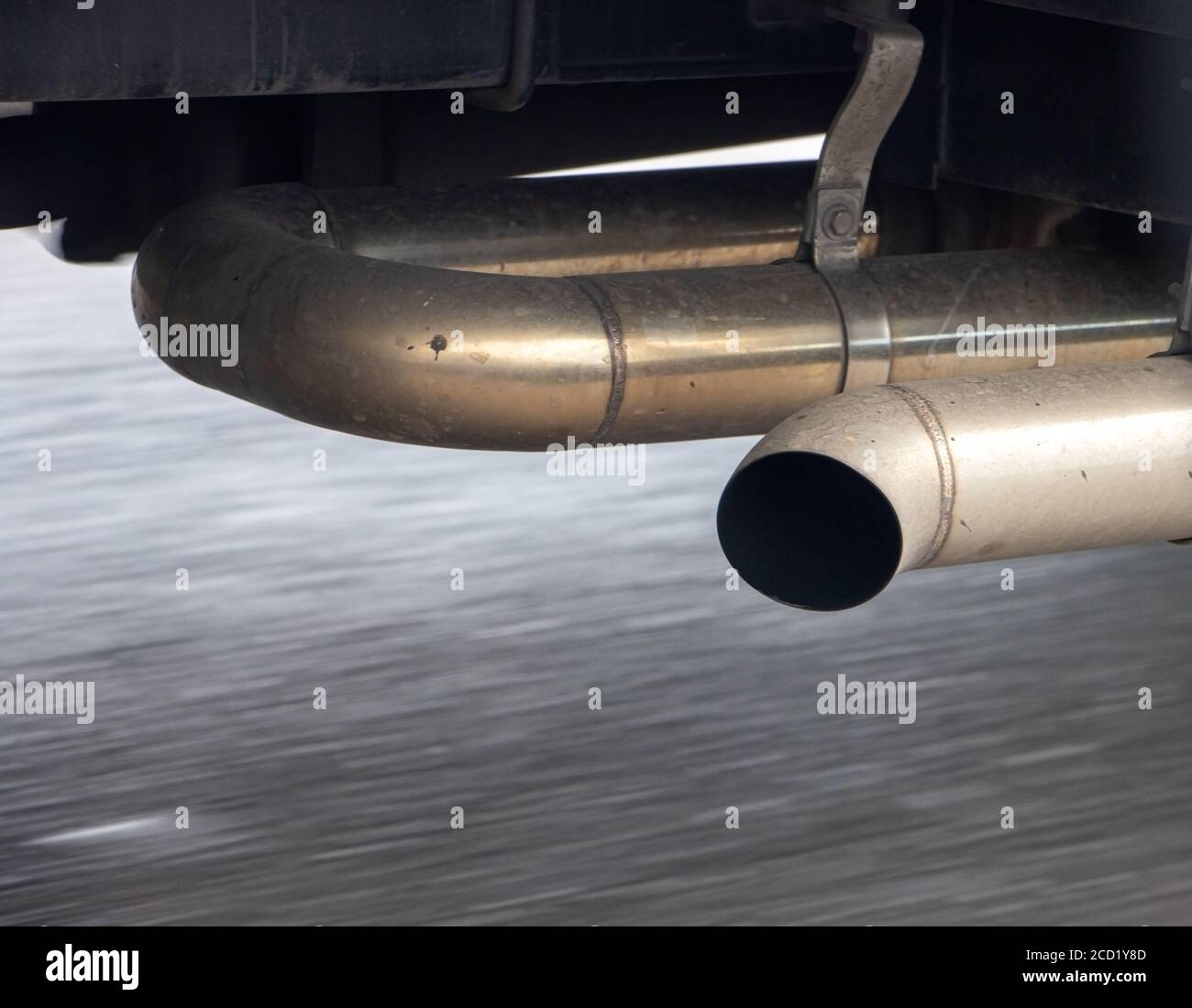 Auspuff eines fahrenden LKW mit Bewegung verschwommen Asphalt der Straße, Nahaufnahme. Stockfoto