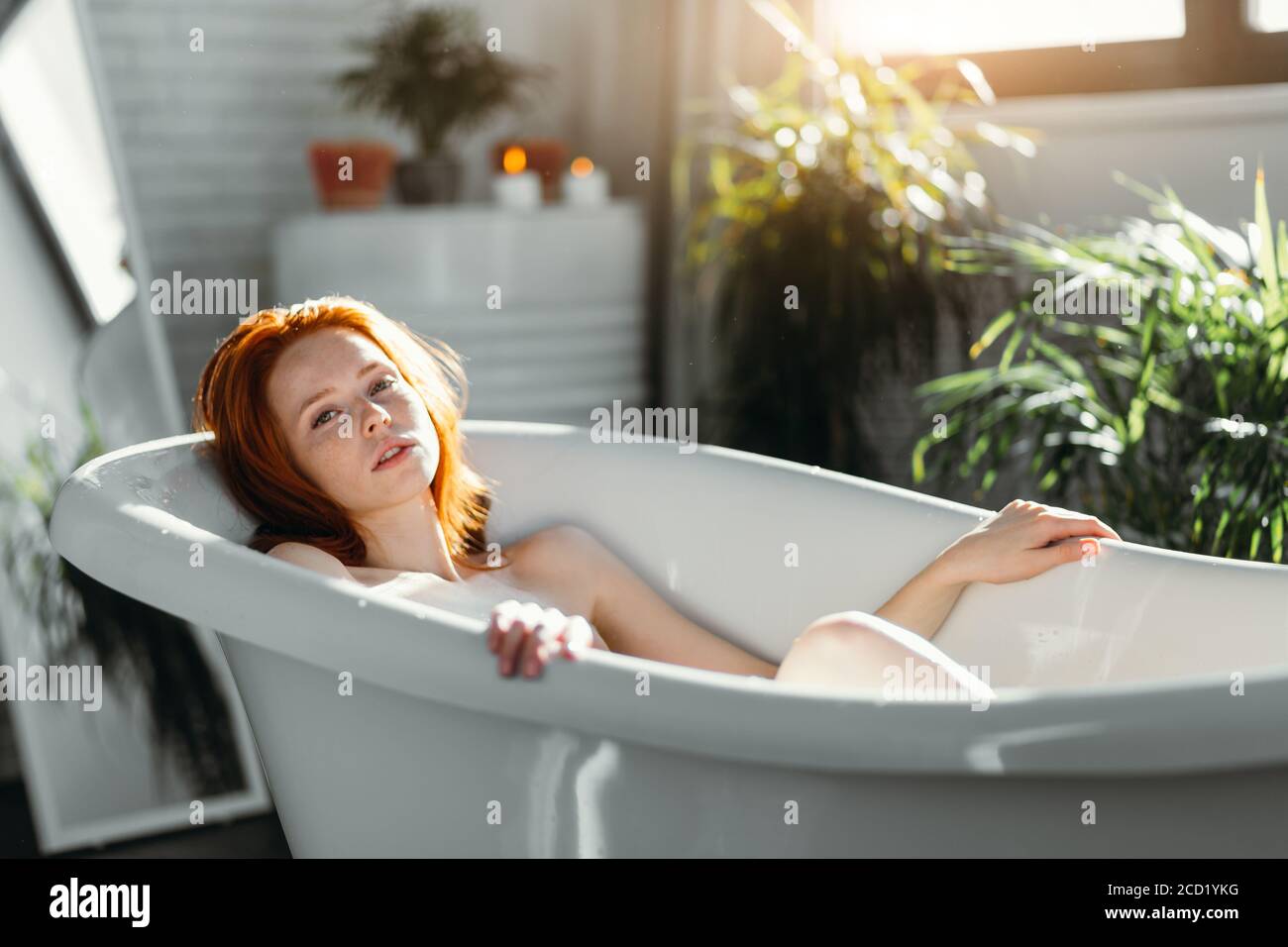 Attraktive rothaarige junge Touristen entspannen sich in der Badewanne des Hotel Spa und genießen die Ruhe, die harmonische Design-Elemente mit premi kombiniert Stockfoto
