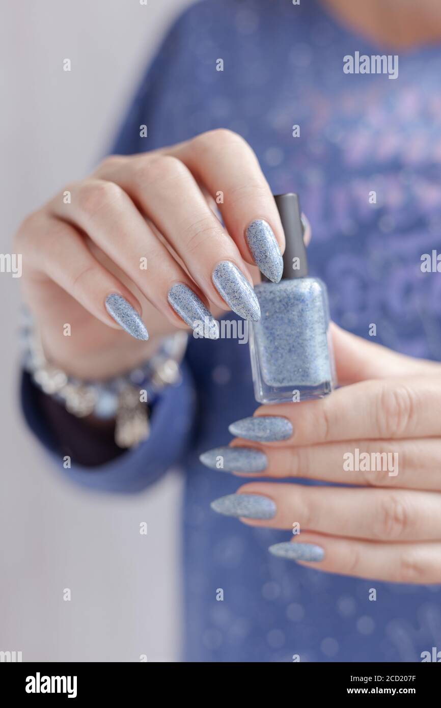 Weibliche Hand mit langen Nägeln und hellblaue Maniküre mit Flaschen  Nagellack Stockfotografie - Alamy