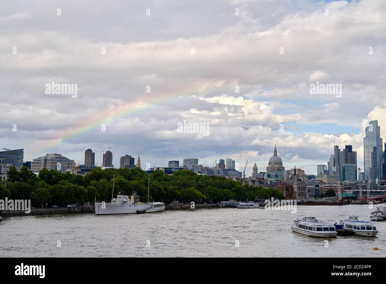 Blick auf die Themse und die City of London. Wolkiger Himmel und Regenbogen im Hintergrund. Stockfoto