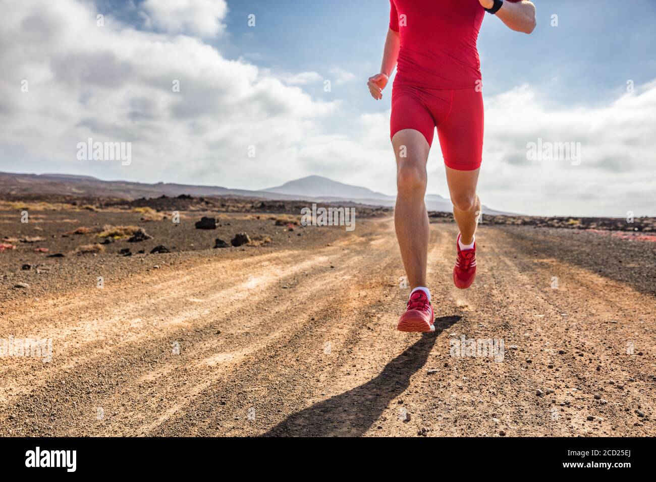 Trail Runner Athlet man läuft auf schmutzigen Bergpfad in roten Kompressionskleidung Outfit und Laufschuhe für extremes Gelände. Stockfoto