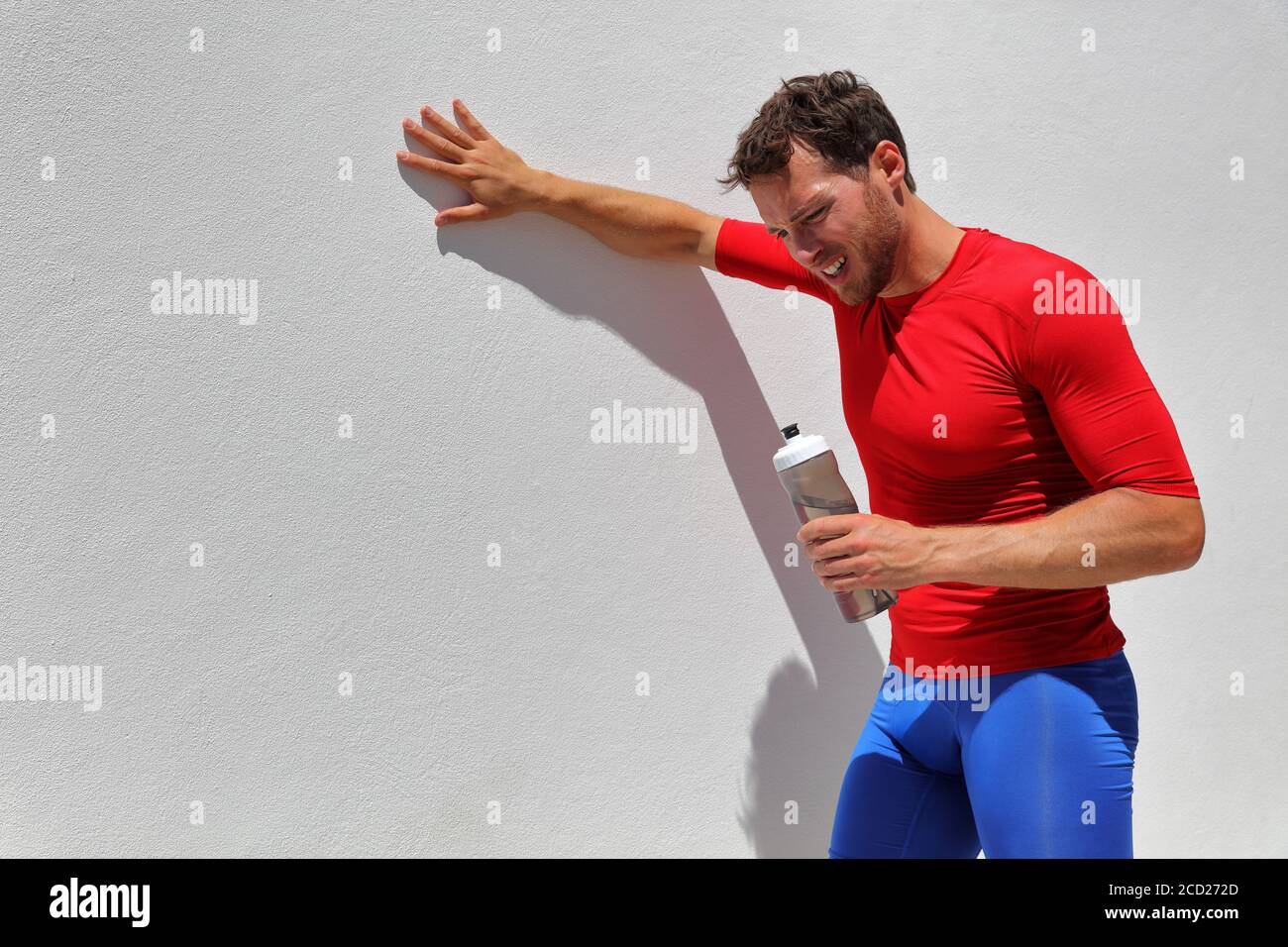 Müde erschöpft dehydrierten Mann Läufer Trinkwasser Flasche nach dem Training. Laufperson, die nach dem Lauf eine Pause einnimmt. Fitness-Athlet atmet von der Sonne Stockfoto