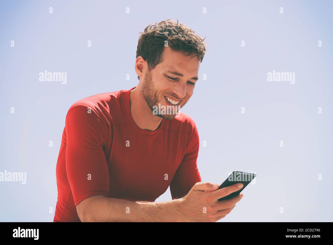 Gesunder Mann, der Video auf dem Handy nach dem Training Trainingseinheit sitzt draußen mit App auf dem mobilen Gerät . Casual junge männliche Erwachsene in seinem Stockfoto