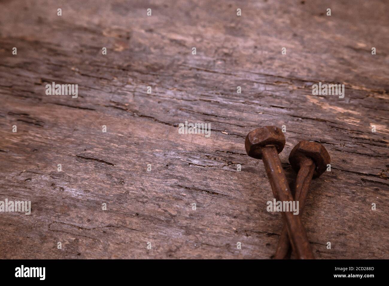 Zwei alte rostige Nägel ruhen auf einem hölzernen Hintergrund. Baukonzept oder religiöses Thema. Stockfoto