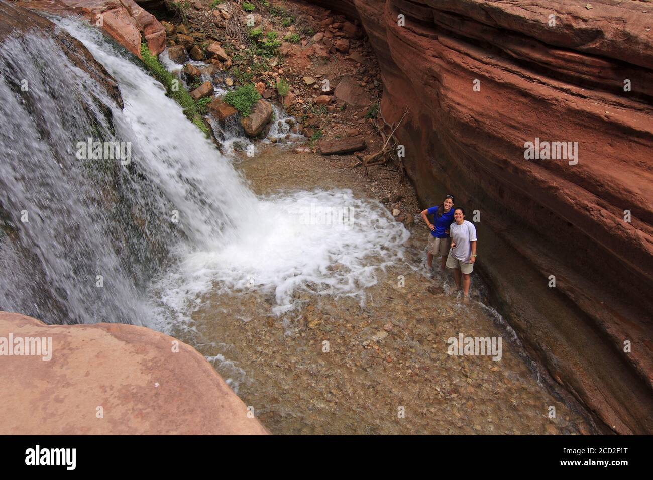 Grand Canyon National Park, Arizona - 18. Mai 2010 - zwei junge Frauen genießen kleinen Wasserfall in Deer Creek auf Sommer Rucksacktouristen. Stockfoto