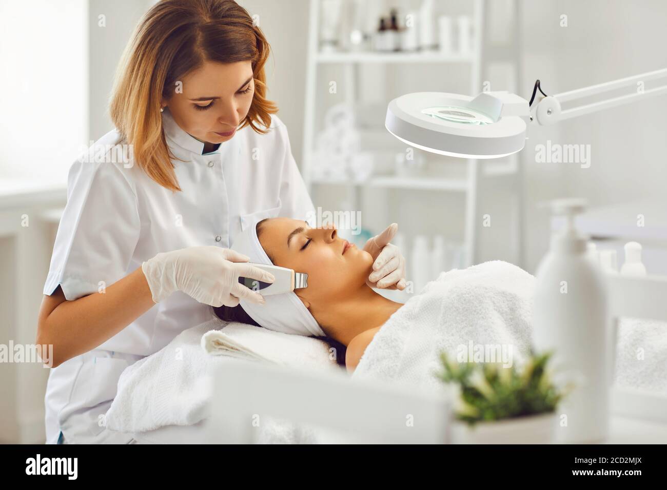 Junge Kosmetologe oder Dermatologe macht Ultraschall Gesichtsreinigung für Frau Im Schönheitssalon Stockfoto