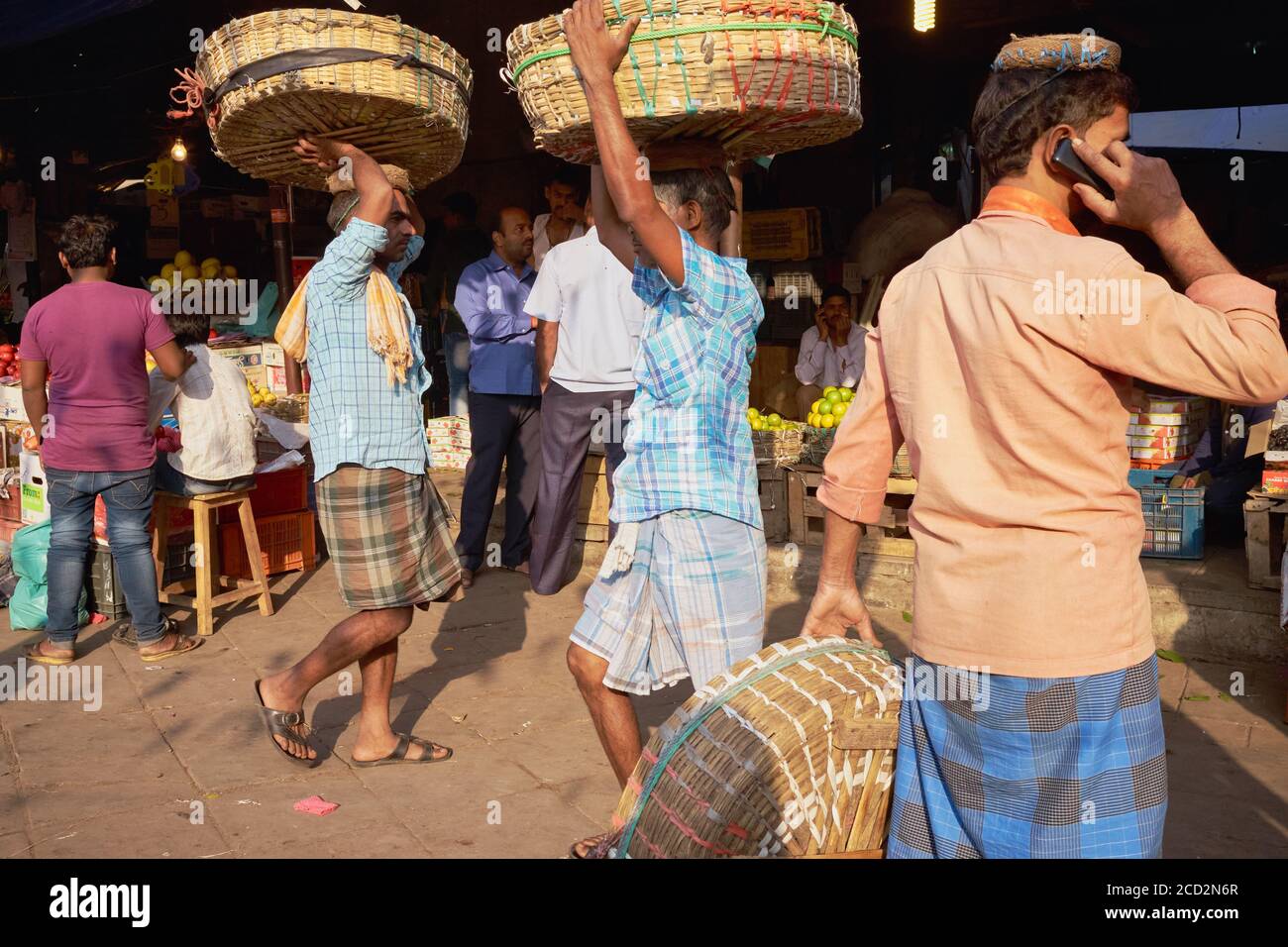 Mahatma Jyotiba Phule Market (Crawford Market), ein Obst- und Gemüsemarkt, Träger, die ihre Körbe tragen, ein Träger, der auf seinem Handy spricht; Mumbai, Indien Stockfoto