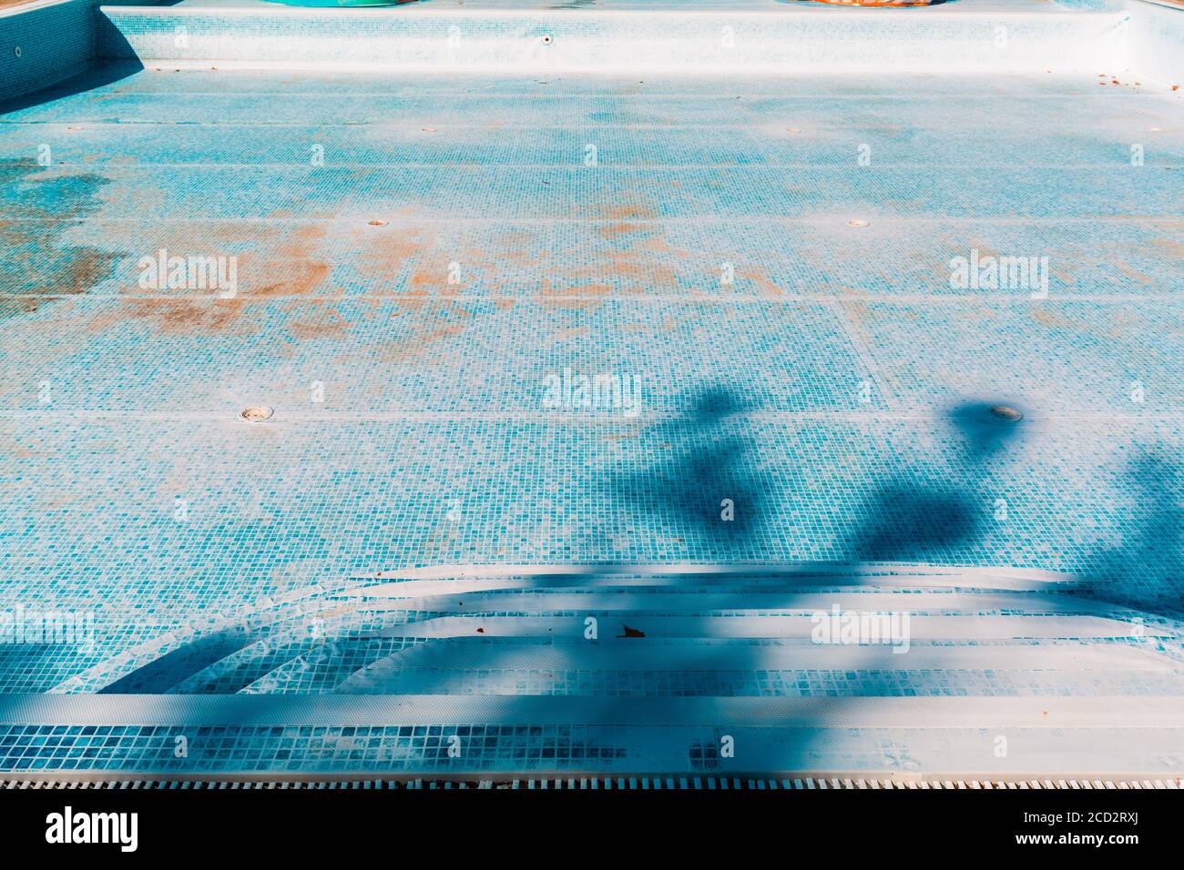 Blauer alter Pool, trocken und schmutzig am Boden. Speicherplatz kopieren. Blick von der Treppe. Konzept der Wartung und Reinigung von Schwimmbädern. Stockfoto