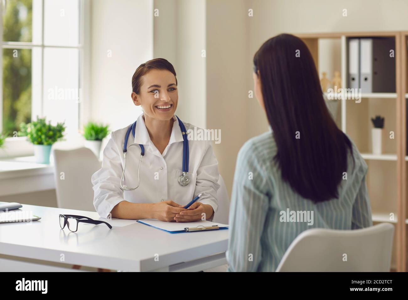 Junge lächelnde Arzt Therapeut Hören Frau Patienten Beschwerden in Medizinische Klinik Stockfoto