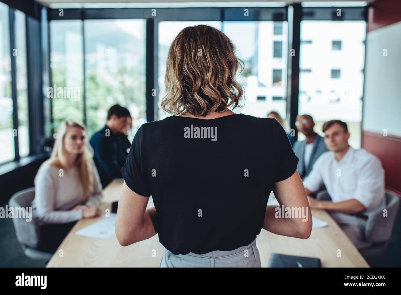 Rückansicht einer Geschäftsfrau bei einer Besprechung im Büro. Die Managerin trifft sich mit ihrem Büropersonal. Stockfoto