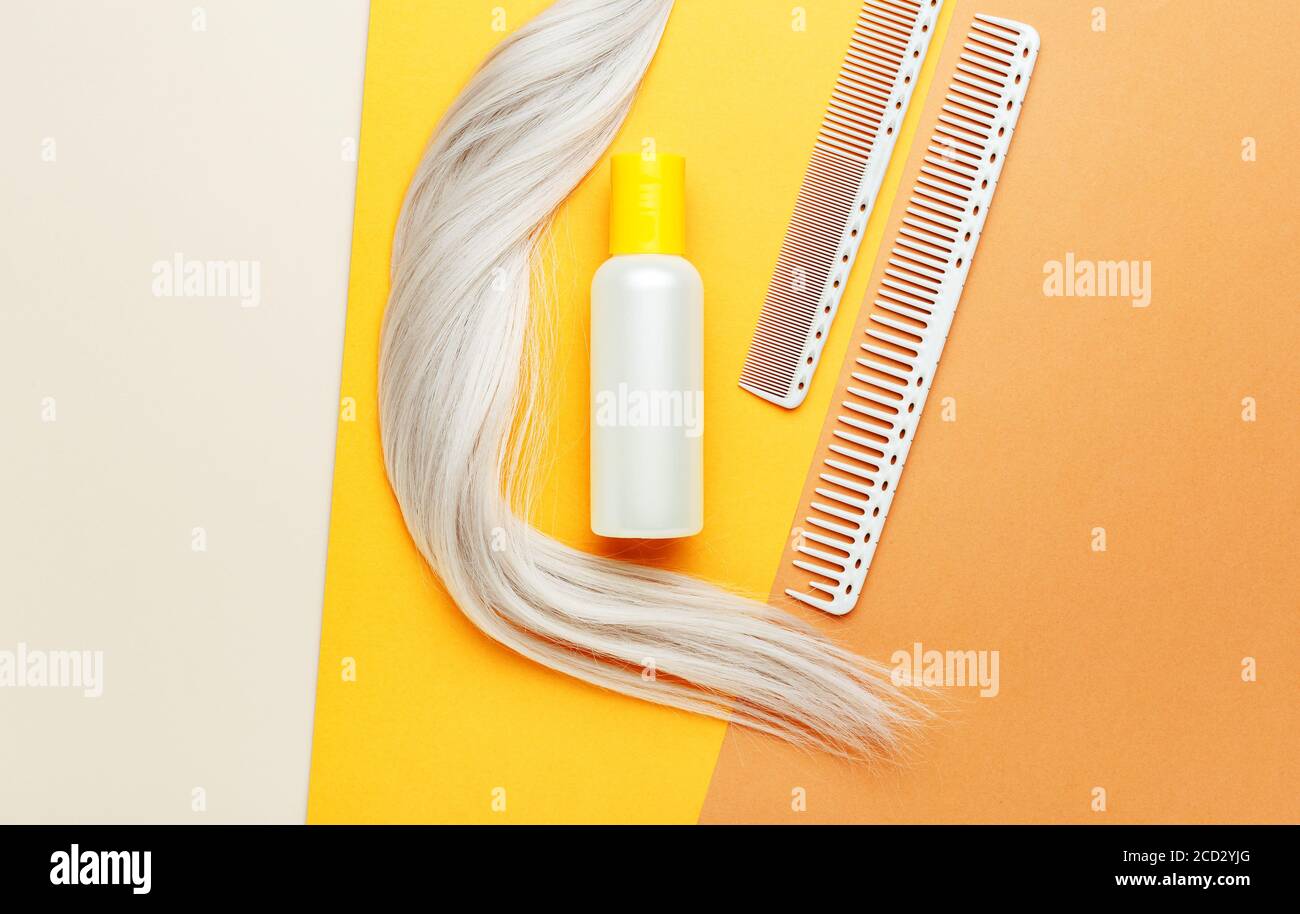 Shampoo orange Flasche mit Locken von blonden Haaren und Kämmen. Friseur-Werkzeuge, Friseursalon Ausrüstung für Friseursalon im Schönheitssalon, Friseur-Shop Stockfoto