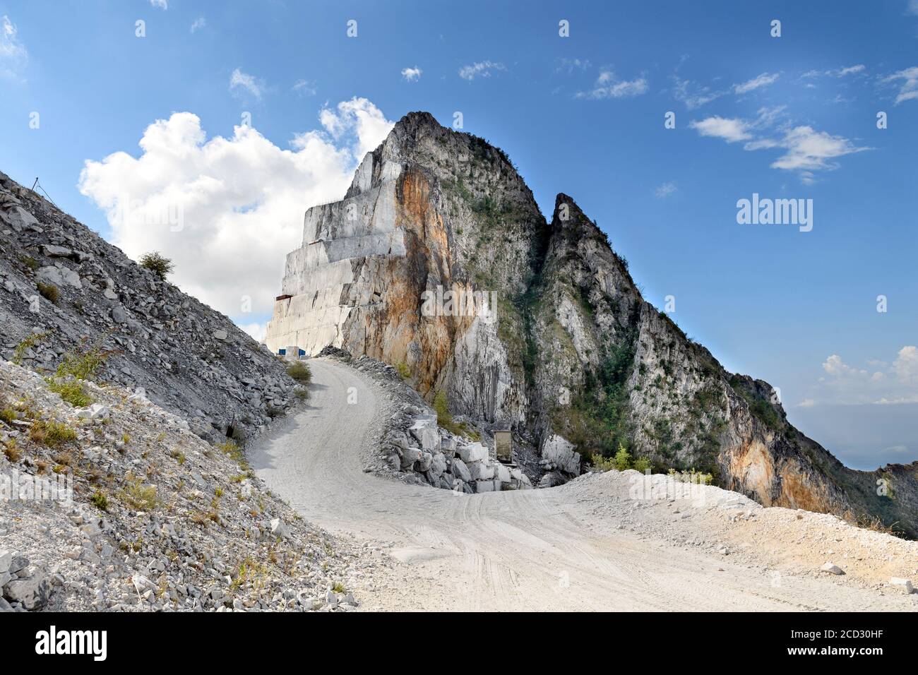 Straße schlängelt sich vorbei an einem ausgegrabenen Berggipfel zeigt die geschnitten Felswände nach dem Abbau von weißem Carrara-Marmor in Toskana Italien Stockfoto