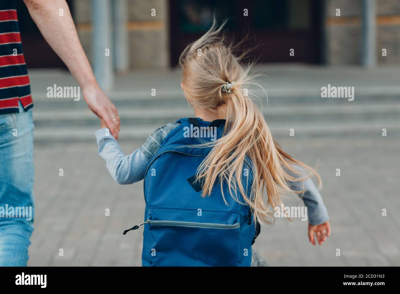 Rückansicht des Vaters, der mit ihm zurück zur Schule ging Tochter trägt Rucksack Stockfoto