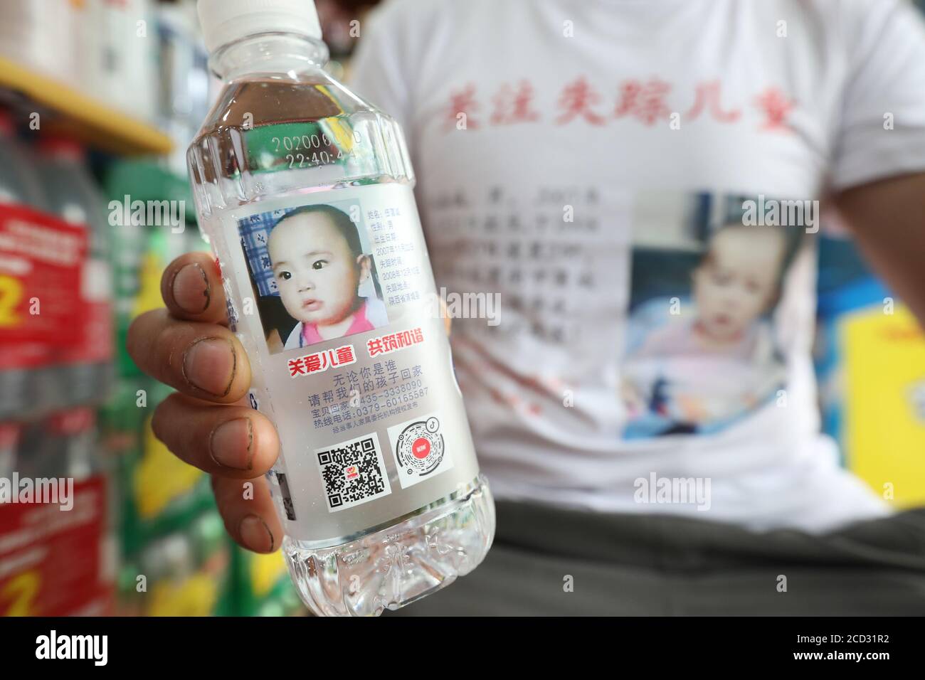 Ein Vater eines vermissten Kindes hält in einem Geschäft in Xi'an, dem nordwestlichen Shaanxi-Profi, eine Wasserflasche mit Foto und Informationen seines Sohnes in der Tasche Stockfoto