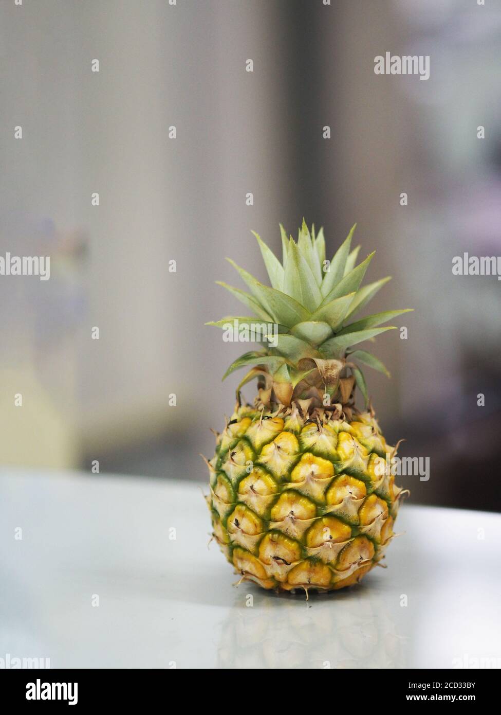Ananas auf dem Glastisch platziert verschwommener Hintergrund Stockfoto