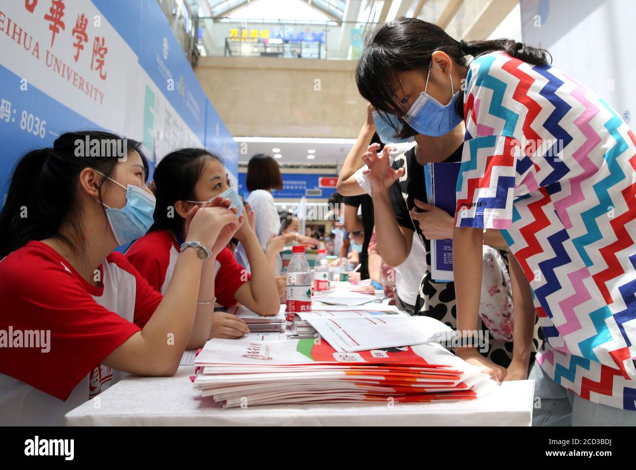 Leute erkundigen sich auf Hochschulen durch einen Hochschulberatungschalter an der Hochschulanwendung Beratungsmesse und Hochschulausstellung in Xi'an Stadt, Nordwesten Chi Stockfoto