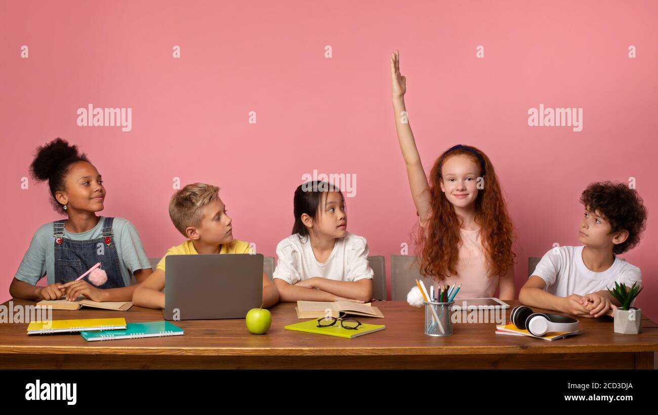 Fleißig rothaarige Mädchen mit Freunden studieren am Schreibtisch vor rosa Hintergrund, leeren Raum Stockfoto