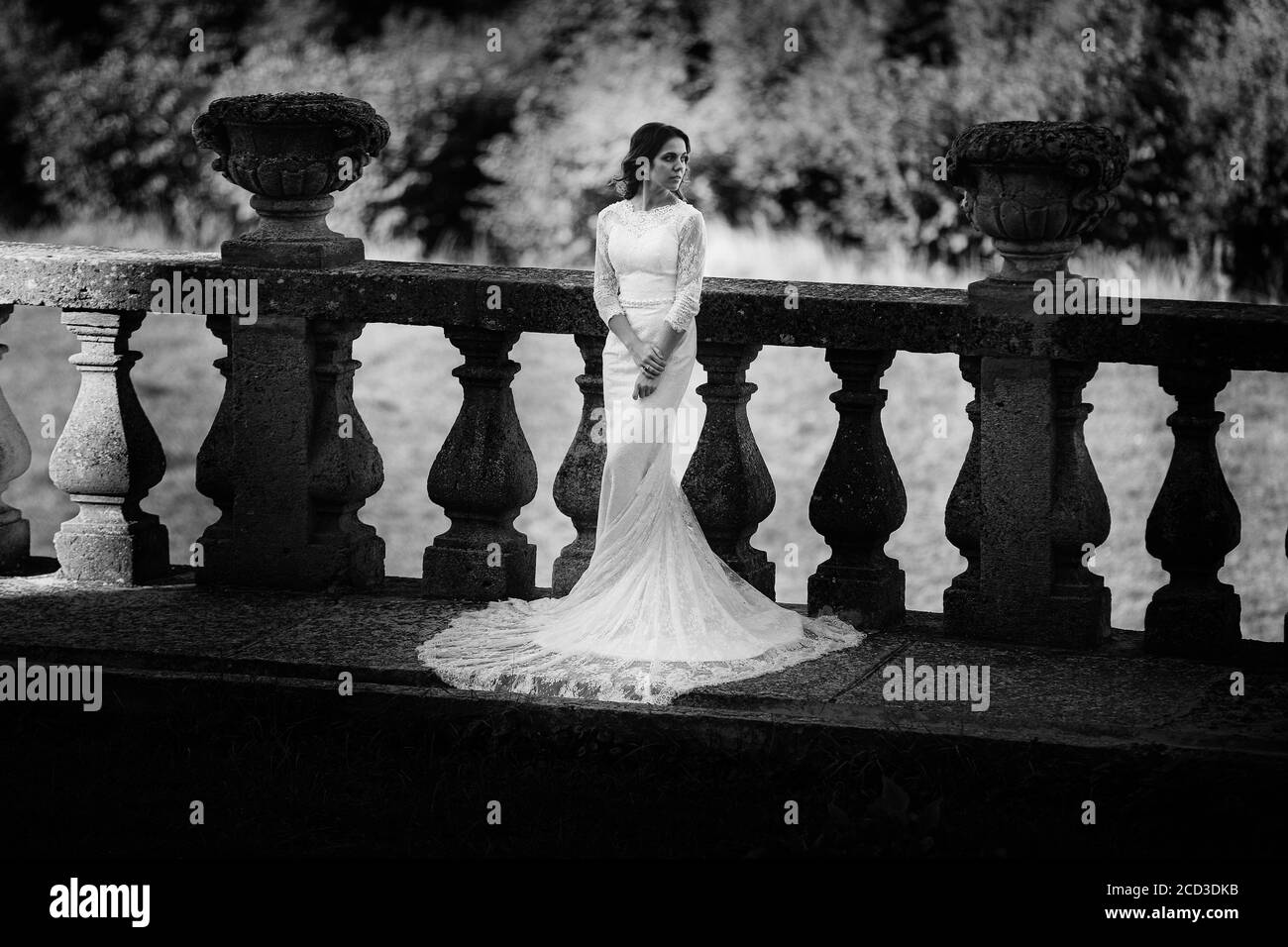 Eine schöne Braut in einem luxuriösen Kleid steht auf einem großen Balkon. Schwarzweiß-Foto Stockfoto
